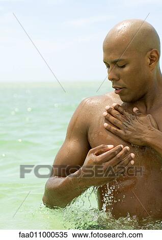 Man standing in sea, splashing chest with water View Large Photo Image Stock Photography - Man standing in sea, splashing chest with water. Fotosearch