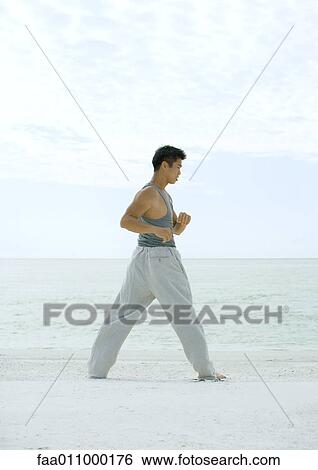 Stock Photograph - Man stretching on beach. Fotosearch