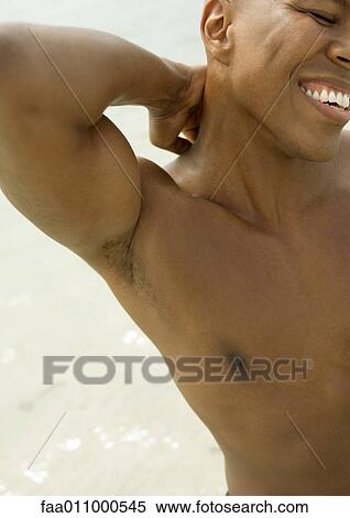 Stock Photography - Man with hand behind neck, smiling. Fotosearch