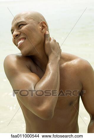 Man with hand on neck, smiling View Large Photo Image Picture - Man with hand on neck, smiling. Fotosearch