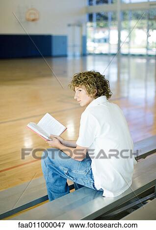 Teen boy reading book on bleachers View Large Photo Image Stock Photo - Teen boy reading book on bleachers. Fotosearch