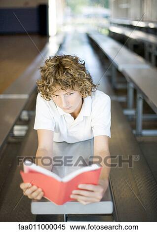 Teen boy reading book on bleachers View Large Photo Image Stock Photography - Teen boy reading book on bleachers. Fotosearch