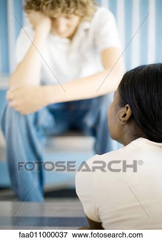 Stock Photo - Teen boy sitting with head down, across from teen girl. Fotosearch