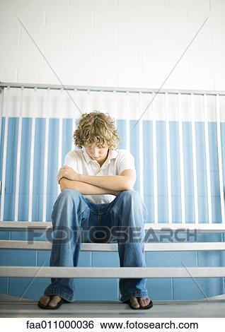 Teen boy sitting with head down on gym bleachers View Large Photo Image Stock Photograph - Teen boy sitting with head down on gym bleachers. Fotosearch