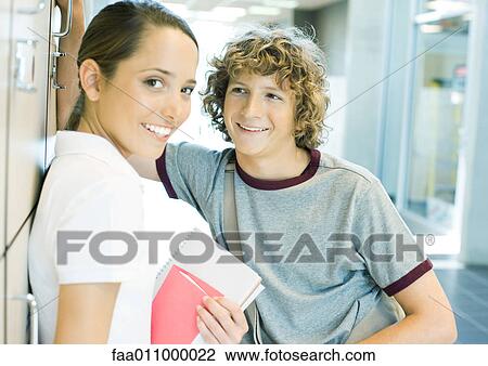 Stock Image - Teen couple leaning against school lockers. Fotosearch