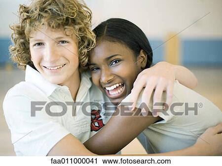 Stock Image - Teen couple sitting with arms around each other. Fotosearch