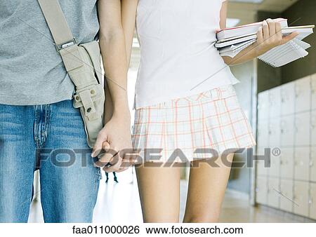 Stock Photograph - Teen couple walking in school hallway, mid section. Fotosearch