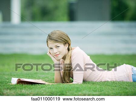 Teen girl lying in grass with book View Large Photo Image Stock Photo - Teen girl lying in grass with book. Fotosearch