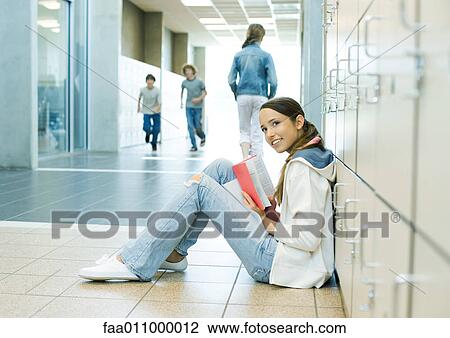 Teen girl sitting on school hallway floor, leaning against lockers View Large Photo Image Stock Image - Teen girl sitting on school hallway floor, leaning against lockers . Fotosearch