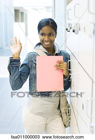 Stock Image - Teen girl standing by locker. Fotosearch