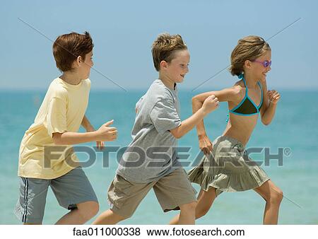Three children racing on beach View Large Photo Image Stock Photo - Three children racing on beach. Fotosearch