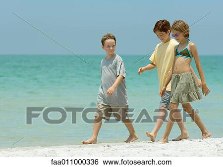 Three children walking next to surf on beach View Large Photo Image Stock Photograph - Three children walking next to surf on beach. Fotosearch