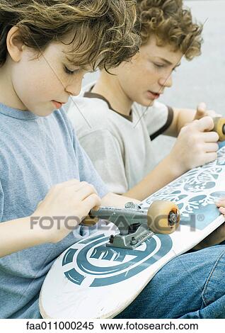 Stock Photography - Two boys looking at wheels of skateboard. Fotosearch