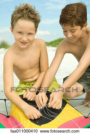 Two boys untangling kite string on beach View Large Photo Image Stock Image - Two boys untangling kite string on beach. Fotosearch
