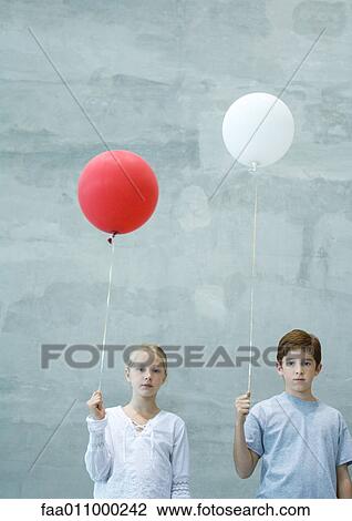Stock Image - Two children holding balloons . Fotosearch