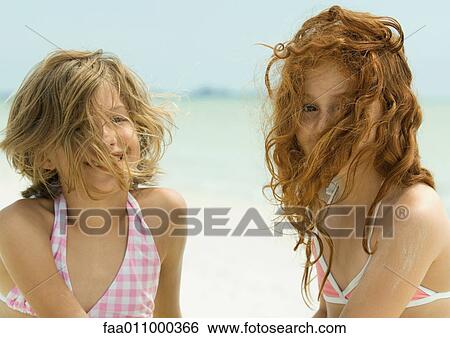 Two girls on the beach with hair in front of faces View Large Photo Image Stock Photograph - Two girls on the beach with hair in front of faces. Fotosearch