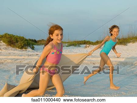 Two girls running on beach, holding blanket out in wind View Large Photo Image Stock Image - Two girls running on beach, holding blanket out in wind. Fotosearch