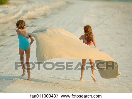 Two girls running on beach, holding blanket out in wind View Large Photo Image Stock Photo - Two girls running on beach, holding blanket out in wind. Fotosearch