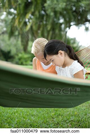 Two girls sitting in hammock together View Large Photo Image Stock Photo - Two girls sitting in hammock together. Fotosearch