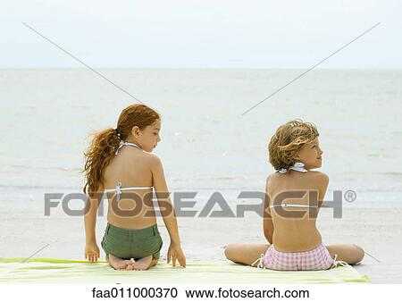 Two girls sitting on beach towel, rear view View Large Photo Image Stock Image - Two girls sitting on beach towel, rear view. Fotosearch