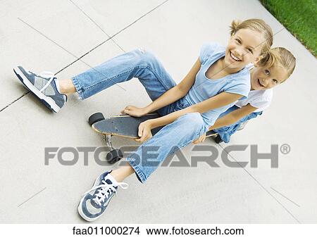 Two girls sitting on skateboard together View Large Photo Image Picture - Two girls sitting on skateboard together. Fotosearch