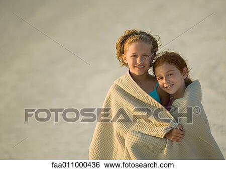 Stock Photograph - Two girls wrapped in towel together at beach. Fotosearch
