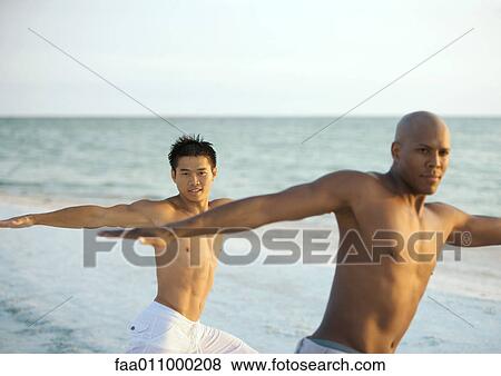 Two men doing relaxation exercise on beach View Large Photo Image Stock Photo - Two men doing relaxation exercise on beach. Fotosearch