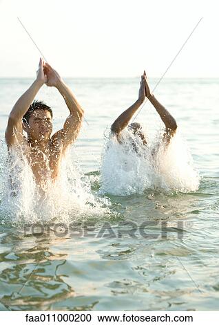 Two men emerging from water View Large Photo Image Stock Image - Two men emerging from water. Fotosearch