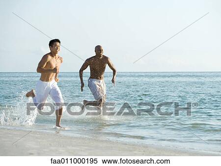 Two men running in surf View Large Photo Image Stock Photography - Two men running in surf. Fotosearch