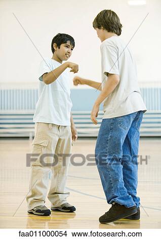 Two teen boys performing special handshake in school gym View Large Photo Image Picture - Two teen boys performing special handshake in school gym. Fotosearch