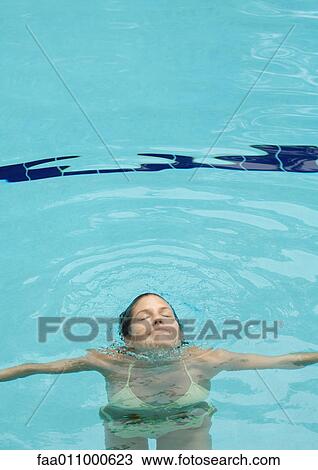 Stock Image - Woman emerging from water, in pool. Fotosearch