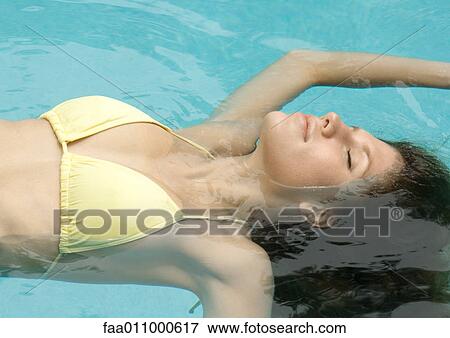 Woman floating on back in pool View Large Photo Image Stock Photo - Woman floating on back in pool. Fotosearch