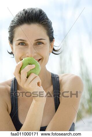 Stock Image - Woman holding up apple, smiling. Fotosearch