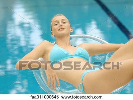 Woman in bikini lounging in transparent chair by pool View Large Photo Image Stock Photography - Woman in bikini lounging in transparent chair by pool. Fotosearch
