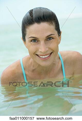 Stock Photo - Woman in water, close-up, smiling at camera. Fotosearch