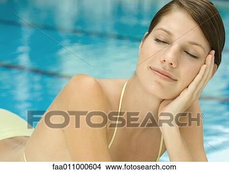 Woman lounging by pool, eyes closed View Large Photo Image Picture - Woman lounging by pool, eyes closed. Fotosearch