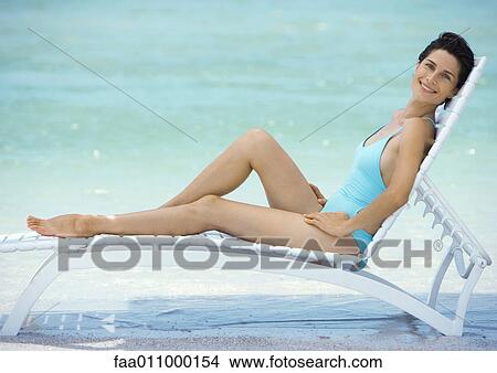 Picture - Woman reclining in lounge chair on beach. Fotosearch