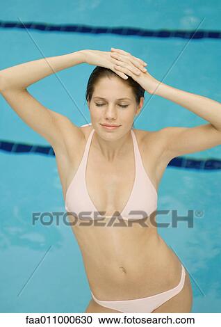 Woman standing by pool, hands and head, eyes closed, smiling View Large Photo Image Stock Image - Woman standing by pool, hands and head, eyes closed, smiling. Fotosearch