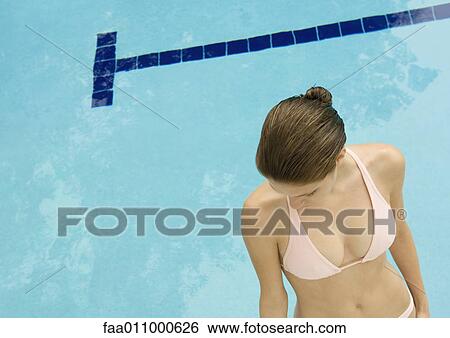 Woman standing by pool, looking down, high angle view View Large Photo Image Stock Photograph - Woman standing by pool, looking down, high angle view. Fotosearch