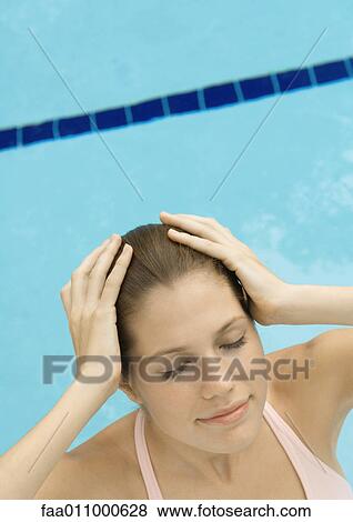 Woman standing by pool, smiling with hands on head View Large Photo Image Stock Photo - Woman standing by pool, smiling with hands on head. Fotosearch