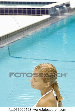 Stock Image - Woman standing in pool, eyes shut. Fotosearch