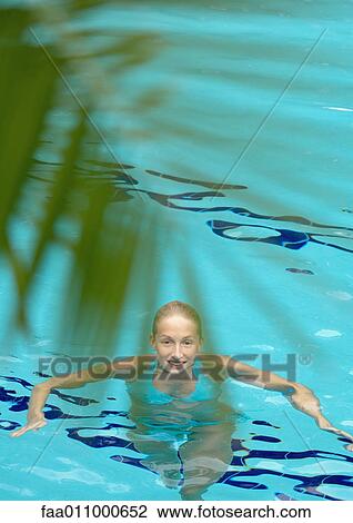 Woman standing in pool, smiling at camera, palm leaf in foreground View Large Photo Image Stock Image - Woman standing in pool, smiling at camera, palm leaf in foreground. Fotosearch