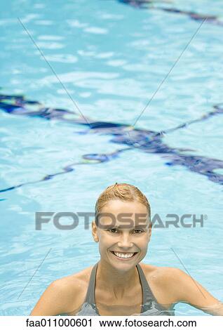 Stock Image - Woman standing in pool, smiling. Fotosearch