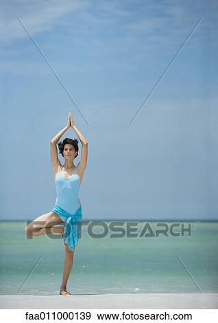 Woman standing on beach in yoga tree pose View Large Photo Image Stock Photo - Woman standing on beach in yoga tree pose. Fotosearch
