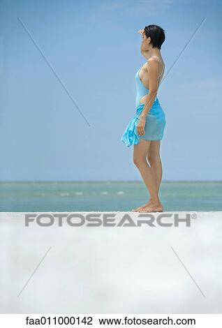 Woman standing on beach, looking at horizon View Large Photo Image Stock Image - Woman standing on beach, looking at horizon. Fotosearch