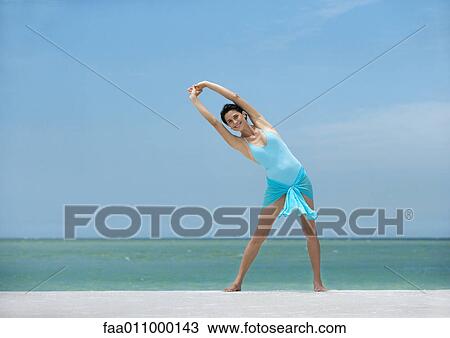 Stock Image - Woman stretching on beach. Fotosearch