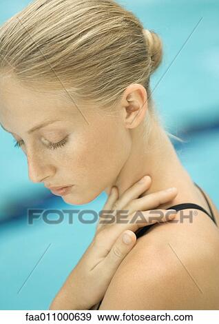 Stock Photo - Woman with hand on shoulder, pool in background. Fotosearch