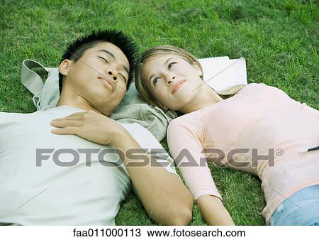 Young couple lying in grass, head to head View Large Photo Image Stock Image - Young couple lying in grass, head to head. Fotosearch