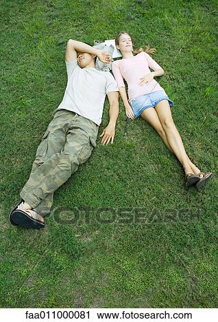 Young couple lying in grass with heads resting on books, high angle view View Large Photo Image Stock Image - Young couple lying in grass with heads resting on books, high angle view. Fotosearch