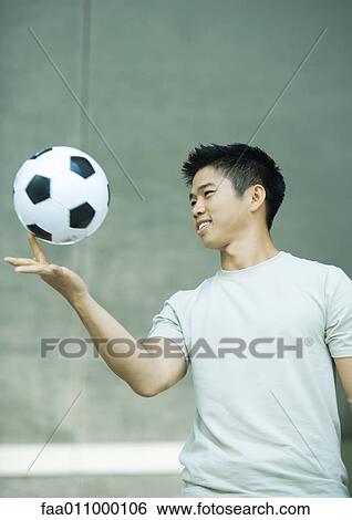 Young man balancing soccer ball on finger View Large Photo Image Stock Photograph - Young man balancing soccer ball on finger. Fotosearch